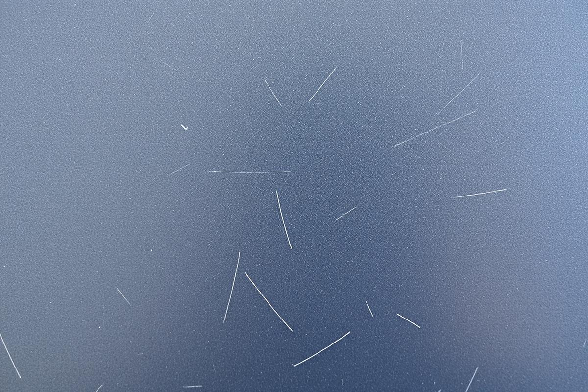 Swirled, hazy paint on a dark blue panel before correction